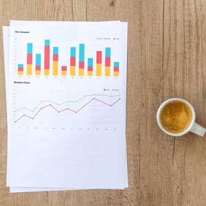 Paper printed with bar and line graph next to cup of coffee